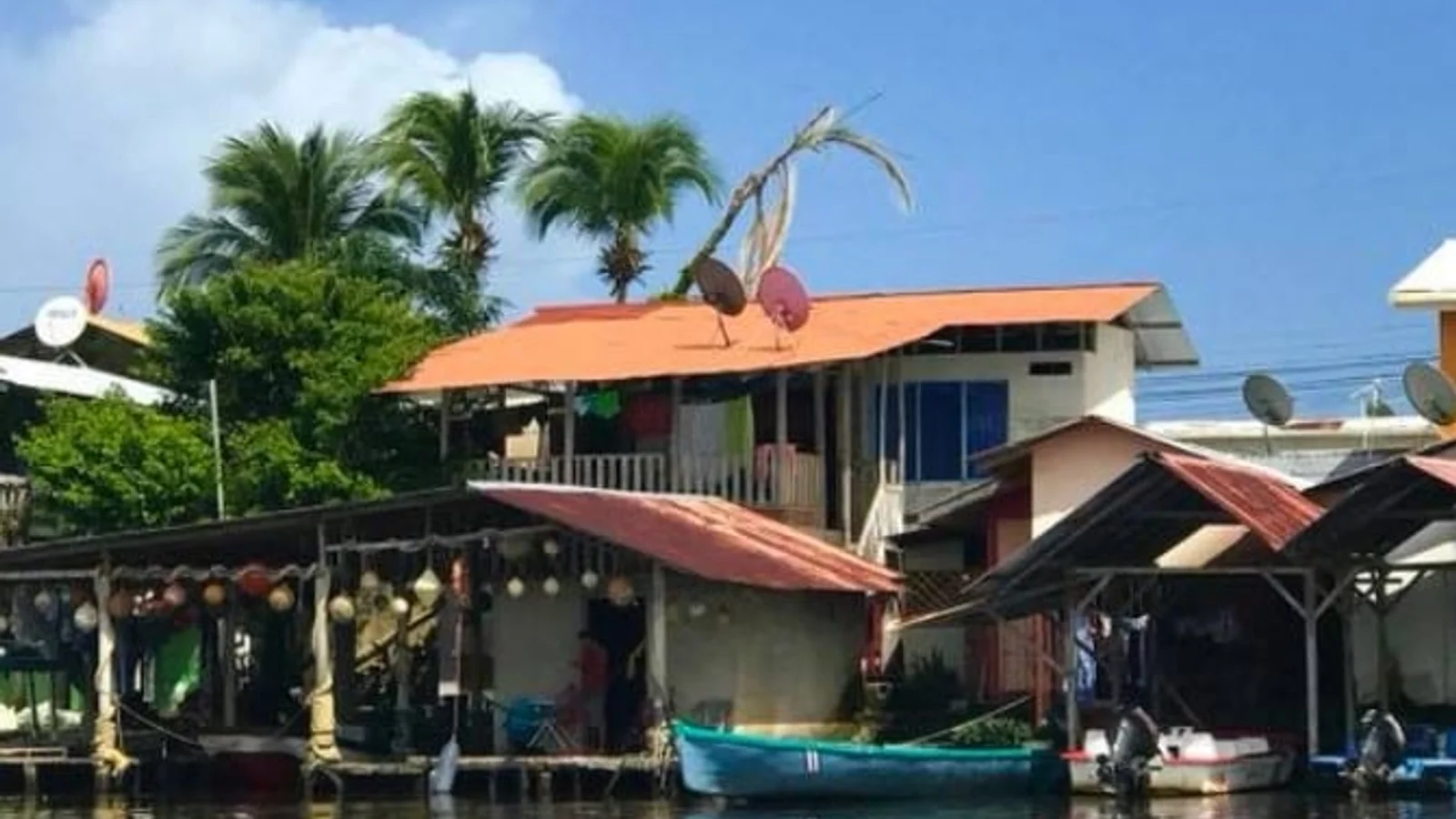 Stilted riverside houses with tin roofs and small boats docked along a canal in Tortuguero
