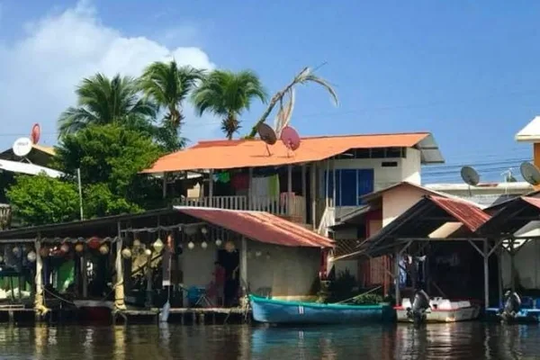 Stilted riverside houses with tin roofs and small boats docked along a canal in Tortuguero