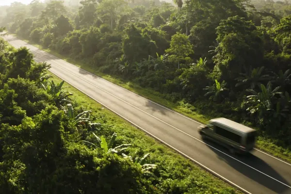 A van drives along a rural highway through lush green jungle in Costa Rica