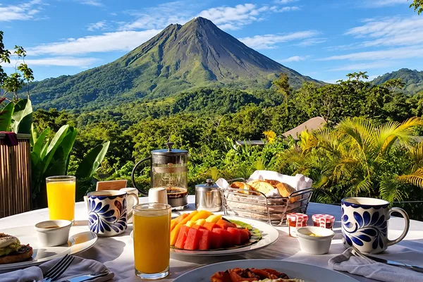 Breakfast table with fruit, juice and coffee overlooking Arenal Volcano and rainforest