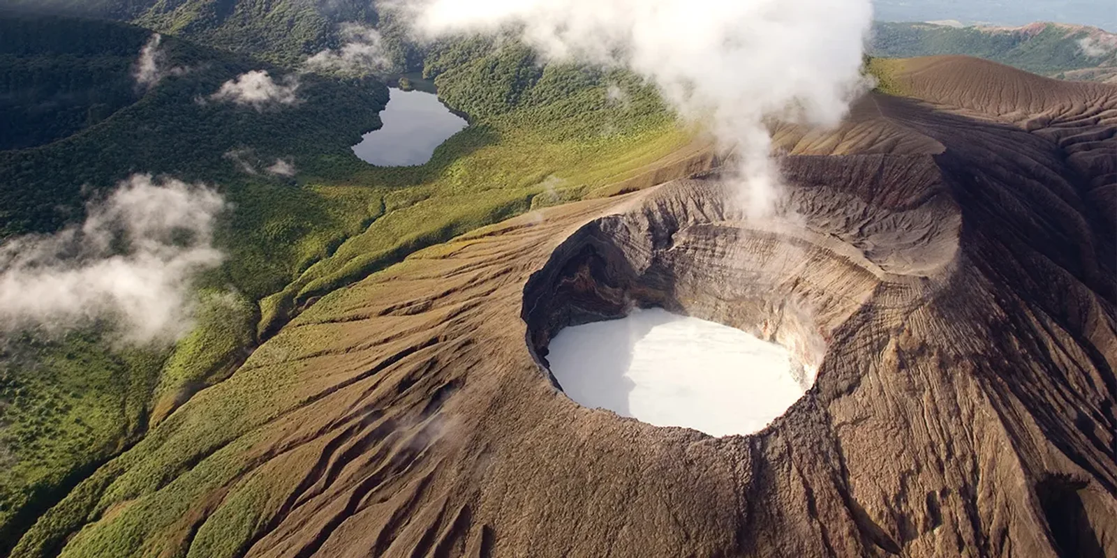 Aerial view of Rincón de la Vieja volcano crater with a turquoise lake and rising steam