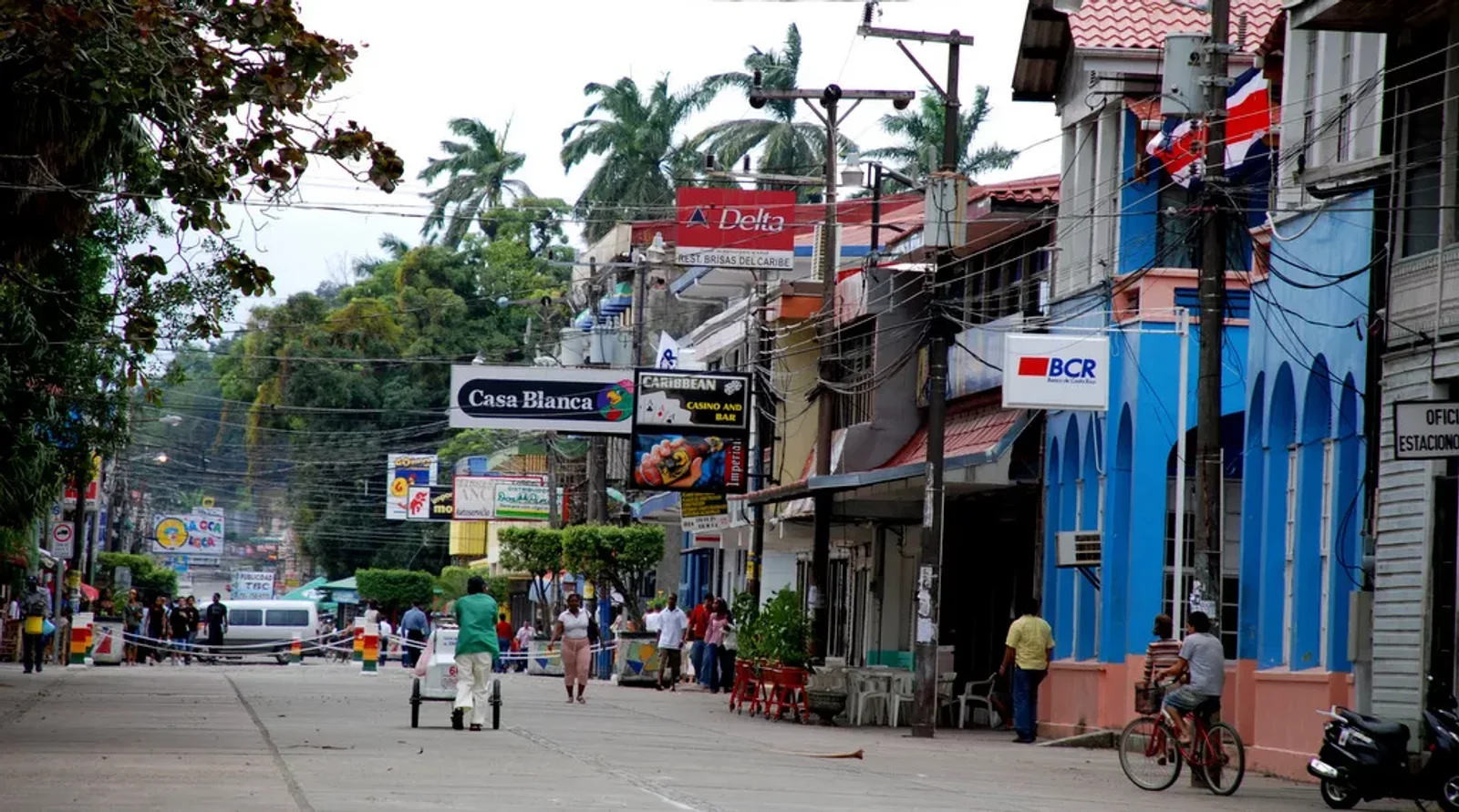 Street scene with shop signs like Casa Blanca and BCR bank, a blue building, pedestrians, and a cyclist