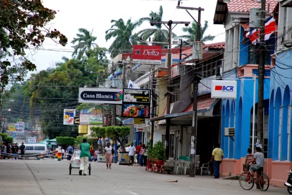 Street scene with shop signs like Casa Blanca and BCR bank, a blue building, pedestrians, and a cyclist