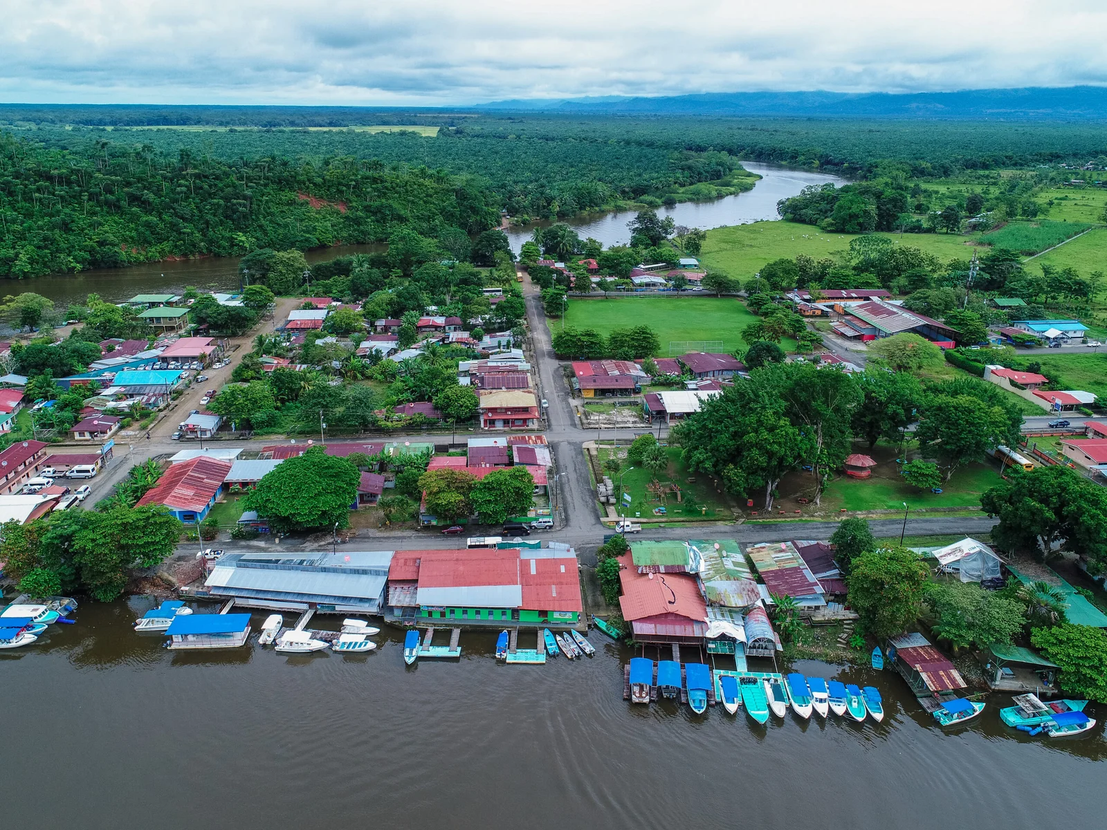 Aerial view of Sierpe village with boats docked along the river and rainforest stretching into the distance