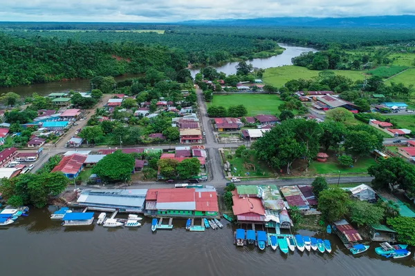 Aerial view of Sierpe village with boats docked along the river and rainforest stretching into the distance