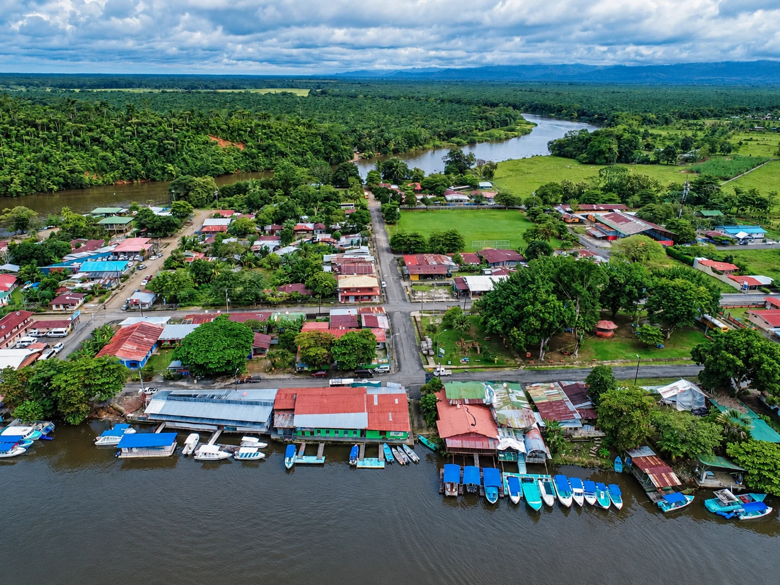Aerial view of Sierpe village with riverside boats docked along the waterfront and surrounding rainforest